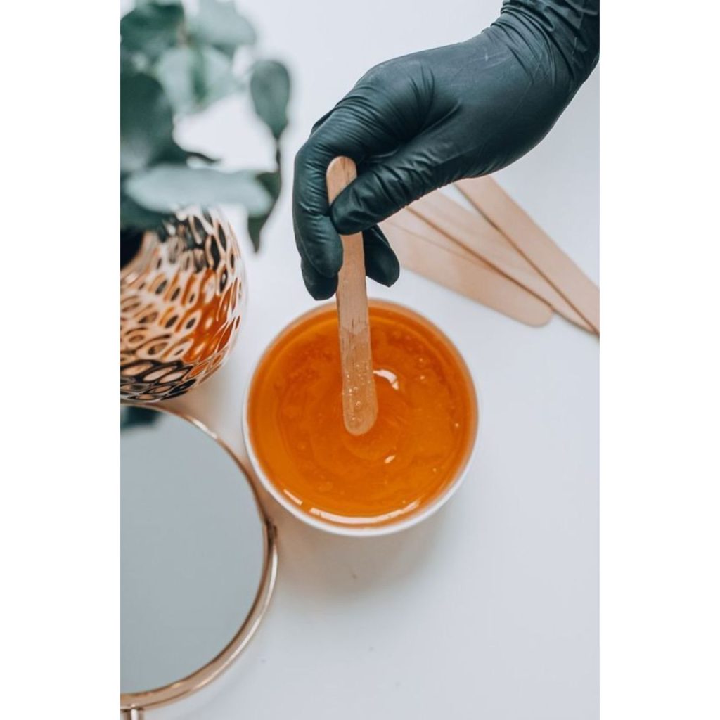 Sugar Wax For Face in a cup with sticks